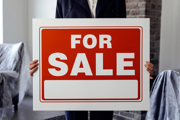 Person holding For Sale sign.