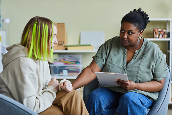 Psychologist supporting sad teenage girl