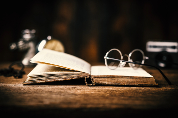 Open book on desk with eyeglasses resting on them